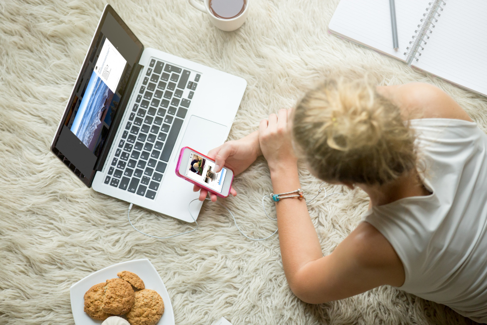 femme allongée avec son pc et son téléphone